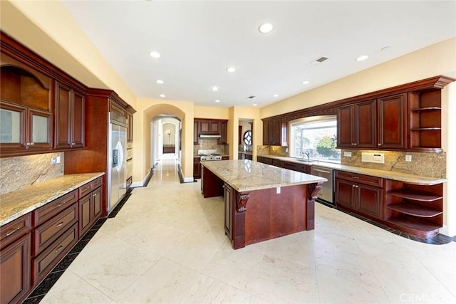 kitchen featuring open shelves, appliances with stainless steel finishes, a sink, and a center island