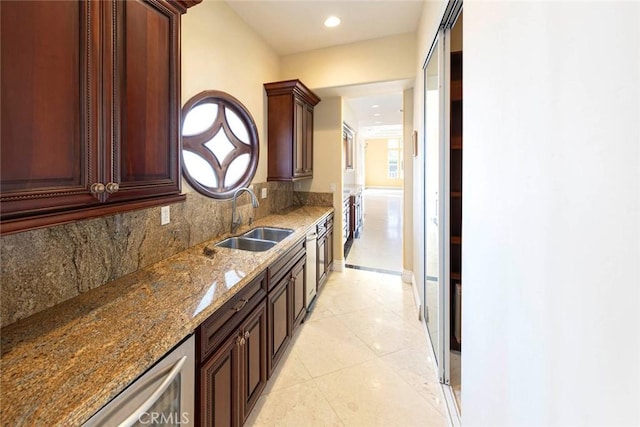 kitchen featuring stone counters, light tile patterned flooring, a sink, and backsplash