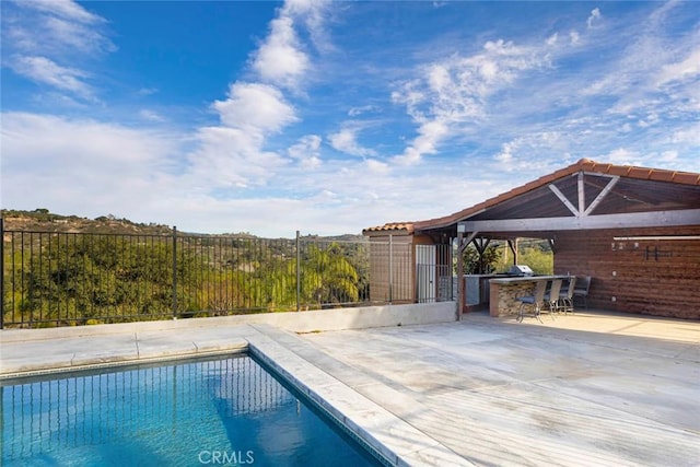 view of pool featuring an outdoor kitchen, fence, outdoor dry bar, a fenced in pool, and a patio area