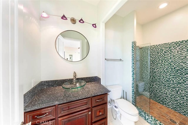 bathroom featuring vanity, a tile shower, and toilet