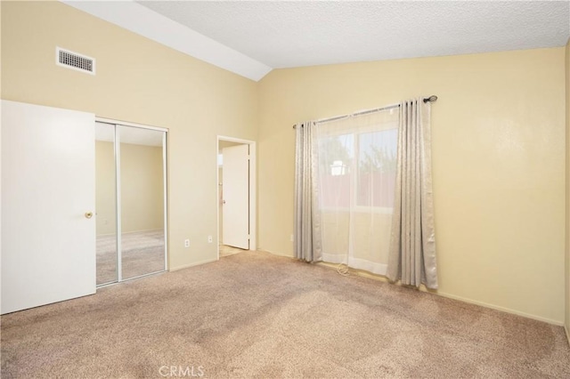 unfurnished bedroom featuring a closet, carpet floors, a textured ceiling, and vaulted ceiling