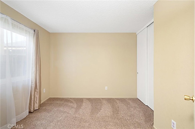 unfurnished bedroom featuring a closet, light colored carpet, and a textured ceiling