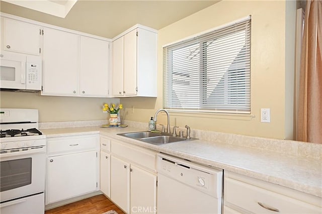 kitchen featuring white cabinets, white appliances, light countertops, and a sink