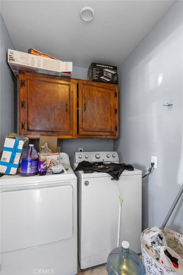 clothes washing area featuring washing machine and clothes dryer and cabinet space