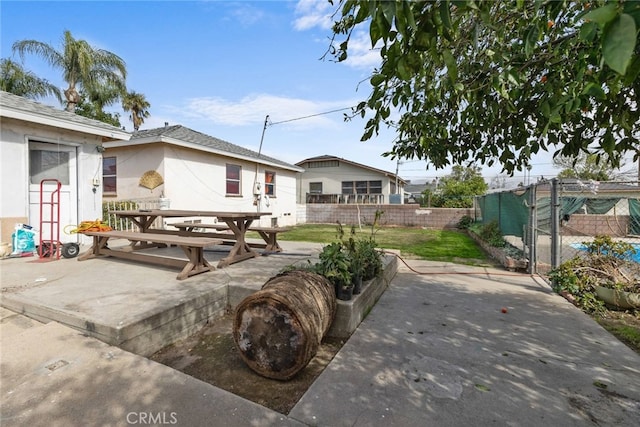 view of front of property featuring stucco siding, outdoor dining space, fence, and a patio