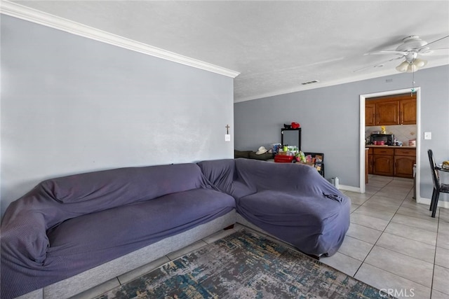 living area featuring light tile patterned floors, ceiling fan, visible vents, baseboards, and crown molding