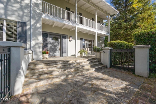 exterior space with a porch, a gate, and a balcony