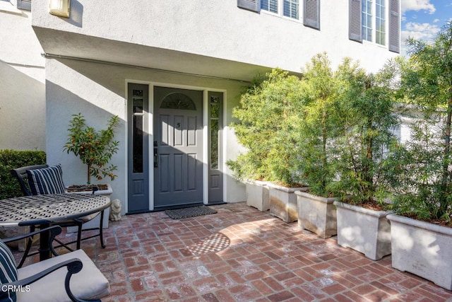 view of exterior entry featuring a patio and stucco siding