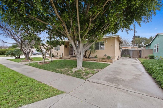 view of front of home featuring a front lawn, fence, a gate, and stucco siding