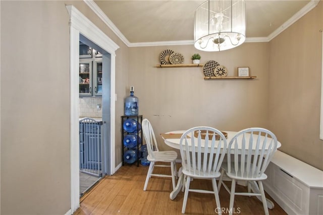 dining room with baseboards, an inviting chandelier, wood finished floors, and crown molding