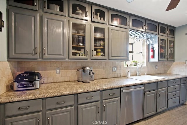 kitchen with gray cabinetry, a sink, and stainless steel dishwasher