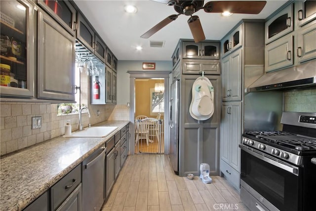 kitchen with visible vents, decorative backsplash, appliances with stainless steel finishes, under cabinet range hood, and a sink