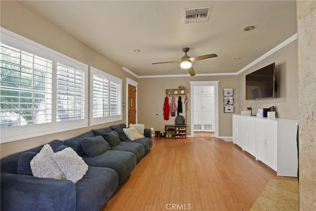 living area with light wood-style flooring, visible vents, a ceiling fan, and ornamental molding