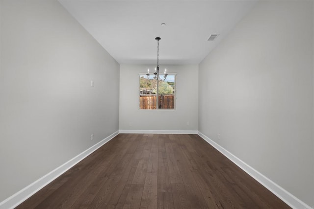 unfurnished dining area featuring dark wood-style floors, visible vents, baseboards, and an inviting chandelier