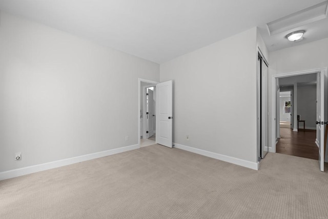 unfurnished bedroom featuring a closet, light colored carpet, and baseboards