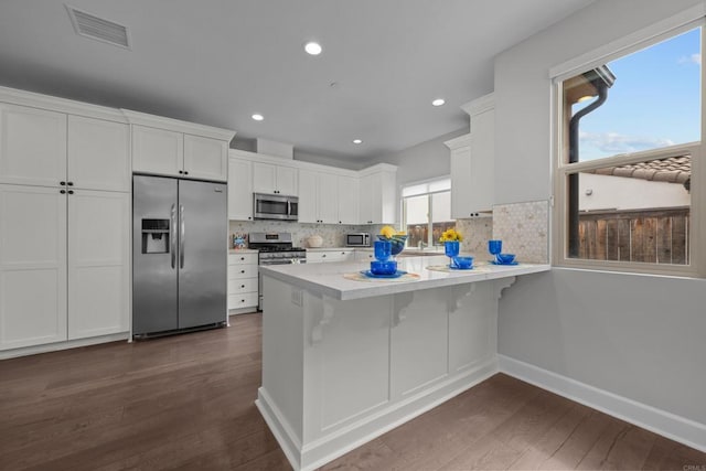 kitchen featuring a peninsula, appliances with stainless steel finishes, visible vents, and white cabinetry