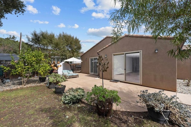 rear view of property with a patio, fence, a tiled roof, and stucco siding