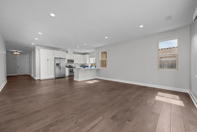 unfurnished living room with dark wood-type flooring, recessed lighting, visible vents, and baseboards