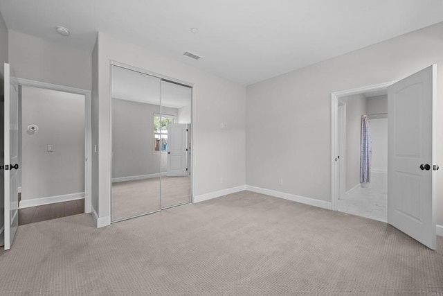 unfurnished bedroom with light carpet, a closet, visible vents, and baseboards