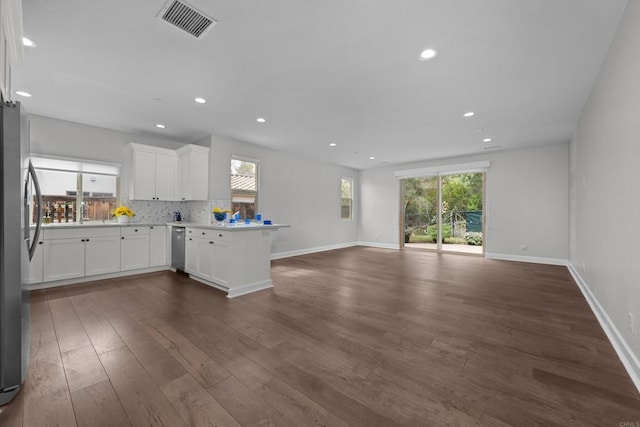 kitchen featuring a peninsula, stainless steel appliances, visible vents, open floor plan, and tasteful backsplash