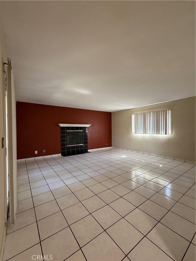 unfurnished room featuring a tiled fireplace and light tile patterned flooring