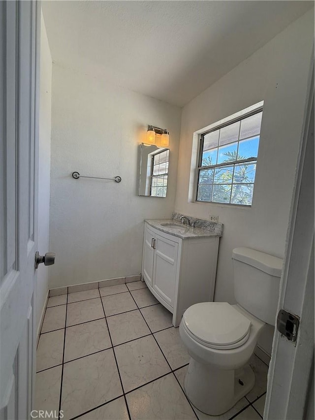 bathroom featuring baseboards, vanity, toilet, and tile patterned floors