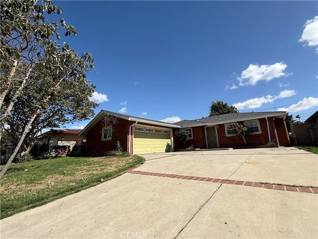 ranch-style house featuring a garage, concrete driveway, and a front lawn