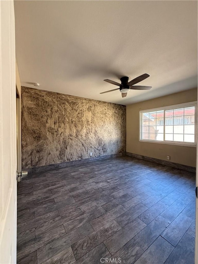 unfurnished room featuring dark wood-style floors, ceiling fan, and baseboards