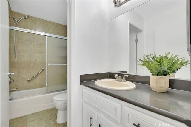 bathroom featuring toilet, tile patterned flooring, combined bath / shower with glass door, and vanity