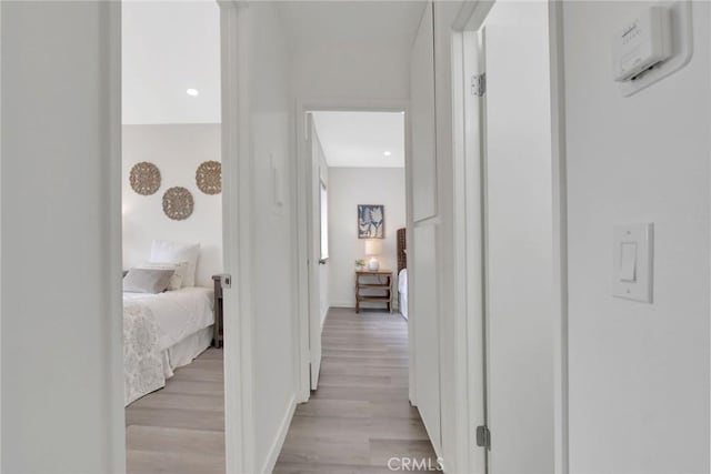 corridor featuring light wood-style flooring and baseboards