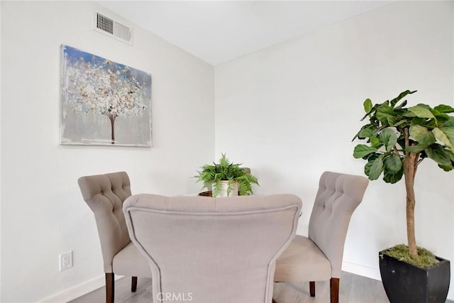 dining area with baseboards, visible vents, and wood finished floors