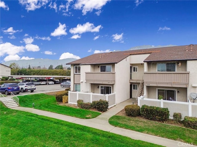 exterior space featuring covered and uncovered parking, fence, stairway, and a mountain view