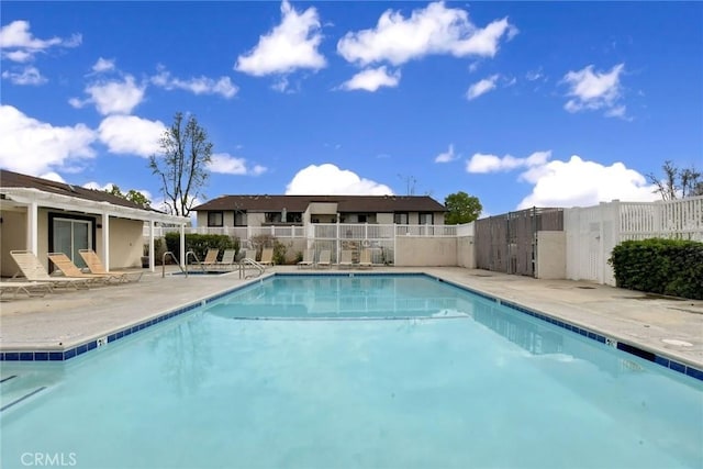 community pool with a patio and fence