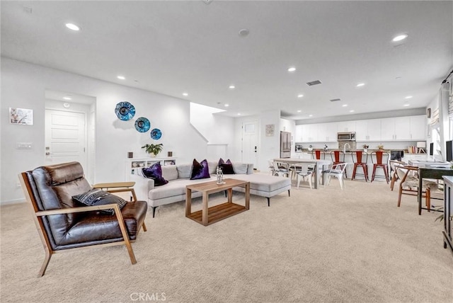 living area featuring recessed lighting, visible vents, and light carpet