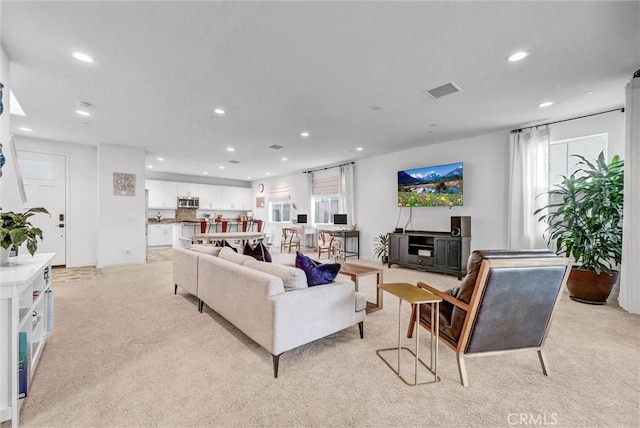 living room with recessed lighting, light colored carpet, and visible vents