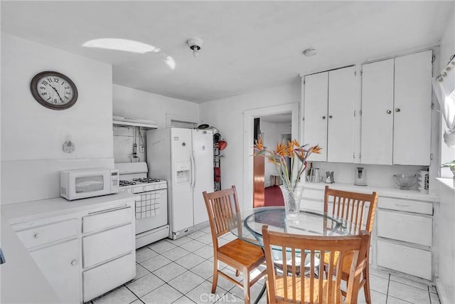 kitchen with under cabinet range hood, white appliances, light tile patterned flooring, and light countertops