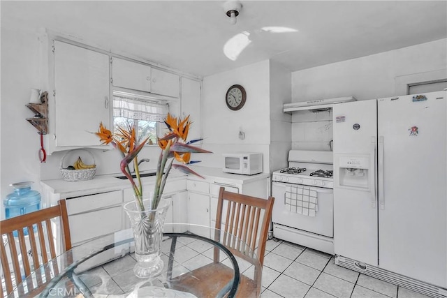 kitchen with under cabinet range hood, white cabinetry, white appliances, light countertops, and light tile patterned floors