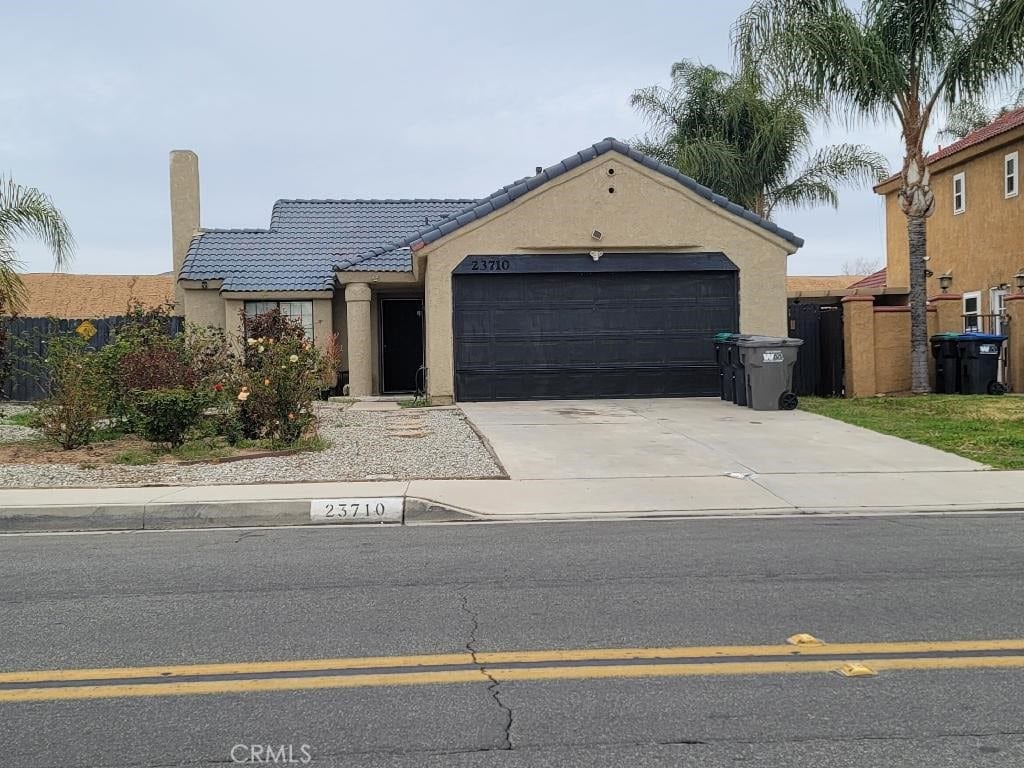 view of front of home featuring stucco siding, fence, a garage, driveway, and a tiled roof