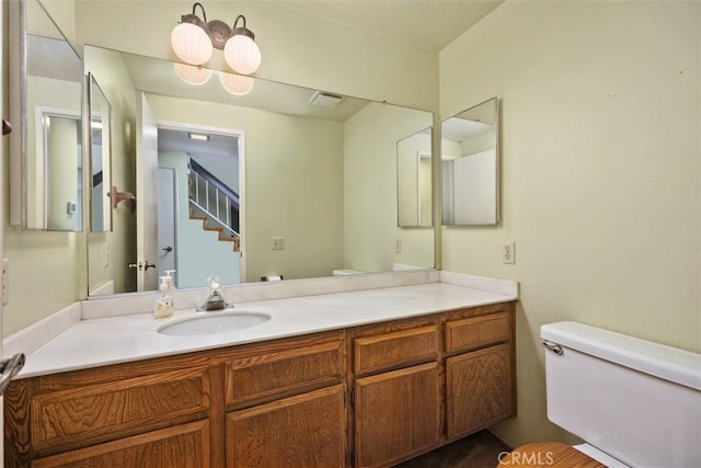 half bath with vanity, toilet, and visible vents