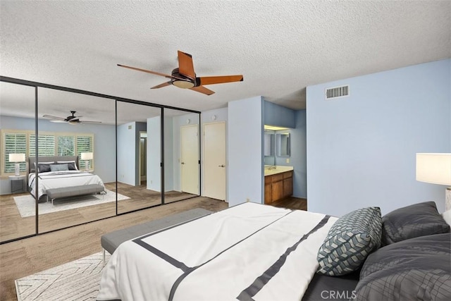 bedroom featuring multiple closets, a ceiling fan, visible vents, and a textured ceiling