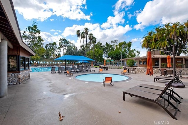 community pool with a patio and fence