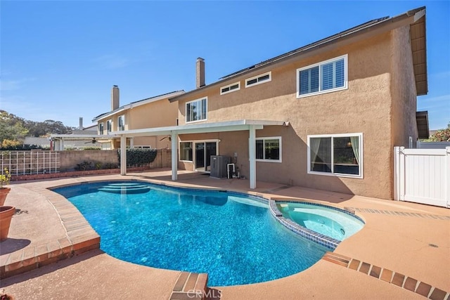 view of pool with a pool with connected hot tub, central air condition unit, a patio area, and a fenced backyard