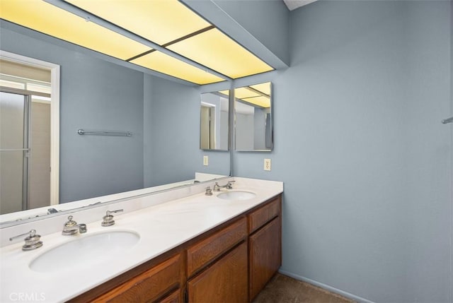 bathroom featuring double vanity, a shower with shower door, and a sink