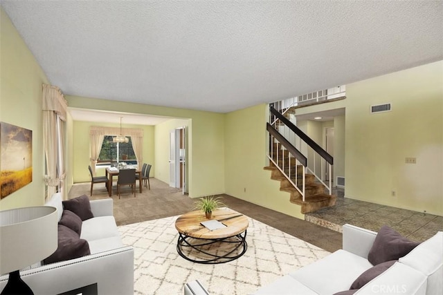 living area featuring stairs, visible vents, a textured ceiling, and carpet flooring