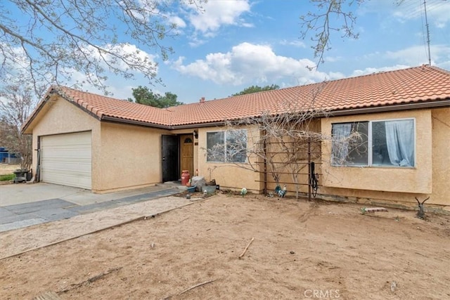 view of front facade with a garage, a tile roof, driveway, and stucco siding