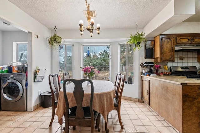 dining area with a textured ceiling, light tile patterned flooring, baseboards, washer / clothes dryer, and an inviting chandelier