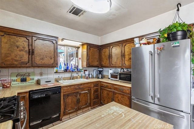 kitchen featuring appliances with stainless steel finishes, light countertops, visible vents, and a sink