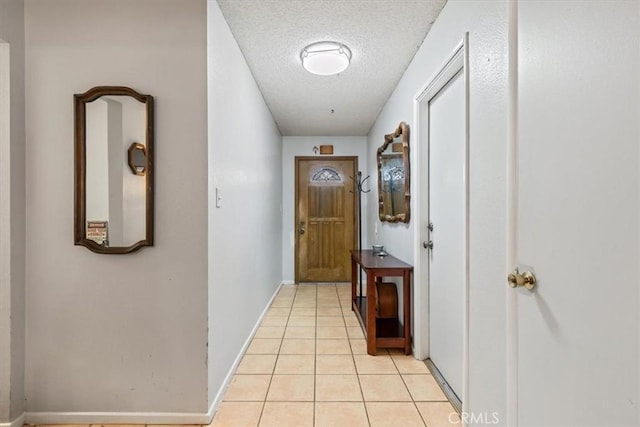 doorway to outside featuring light tile patterned floors, baseboards, and a textured ceiling