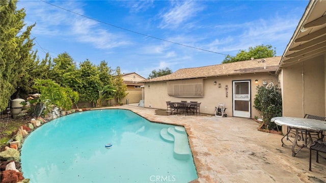 view of swimming pool featuring a patio, outdoor dining space, and fence