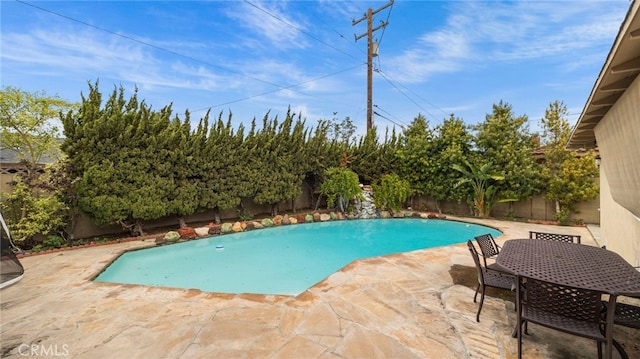 view of swimming pool with a patio area, a fenced backyard, a fenced in pool, and outdoor dining space